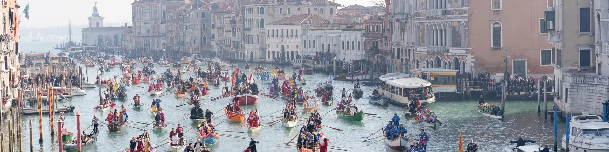Colorful regatta on the Grand Canal in Venice with a multitude of boats and costumed rowers, creating a vibrant spectacle.